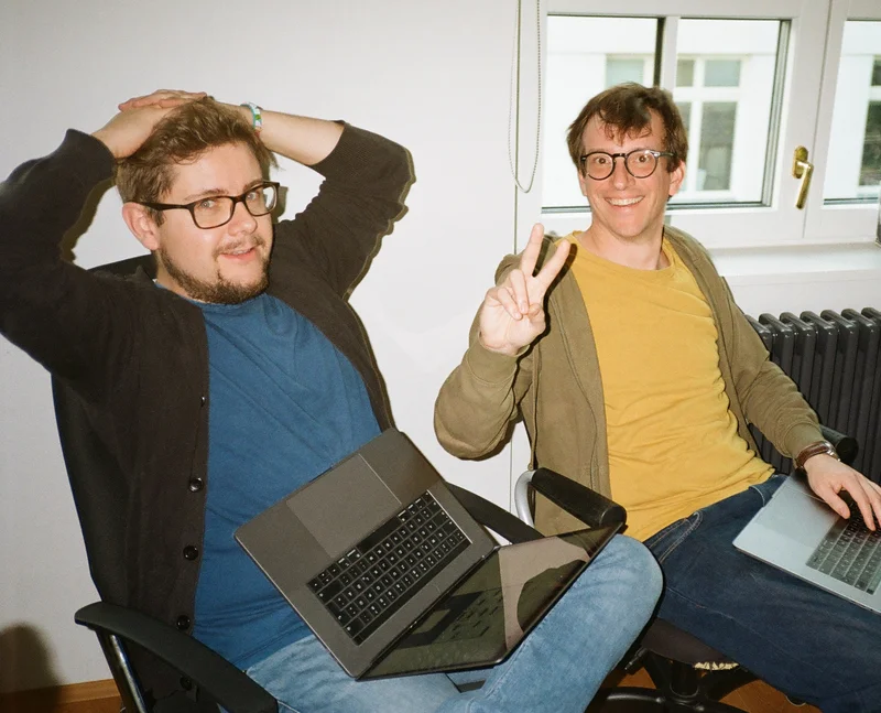 Stephan und Lukas sitzen mit Mac am Schoss, Lukas zeigt ein Peace Zeichen in die Kamera